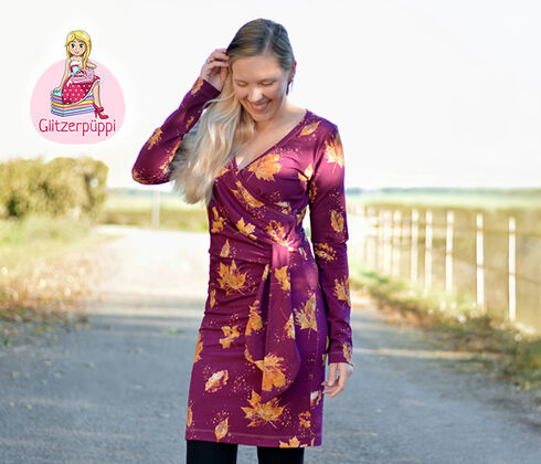 Woman in burgundy jersey dress with golden leaves, next to stacked brown, black, burgundy and dark blue leaf pattern jerseys