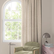 Window with colorful floral curtain in red, orange and blue, green armchair and small table with lamp